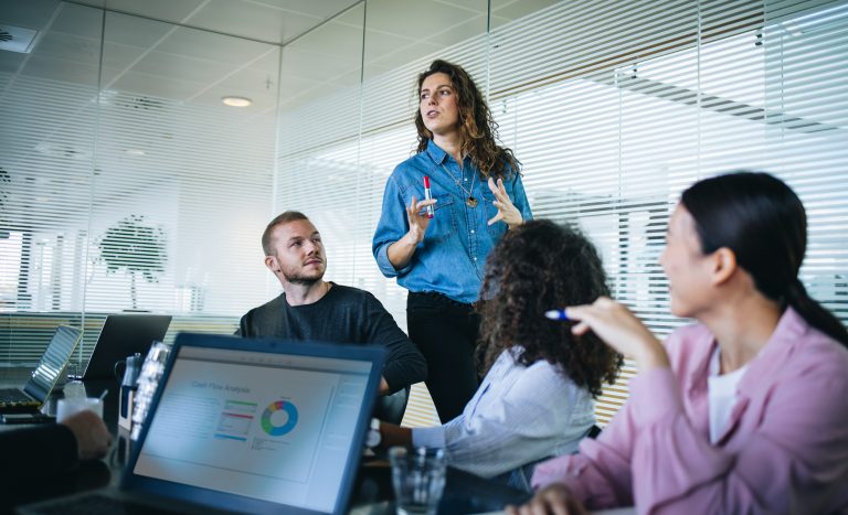 Woman in boardroom talking and leading business meeting with peers